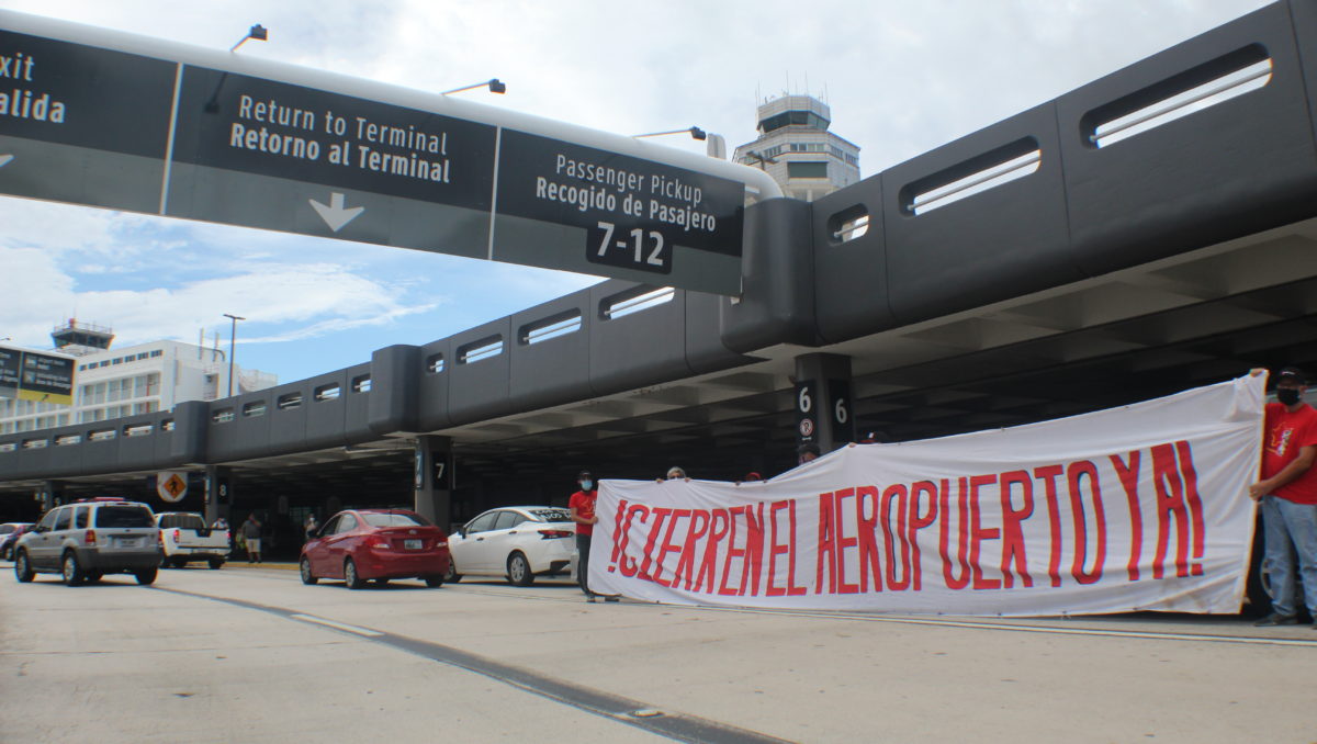 Caravana manifestación y pancarta grande diciendo Cierren el Aeropuerto Ya en el Aeropuerto Internacional