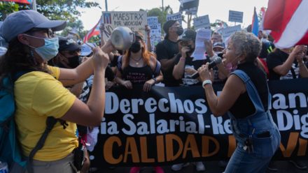 Personas protestando. Pancarta. Mujer con megáfono en mano.